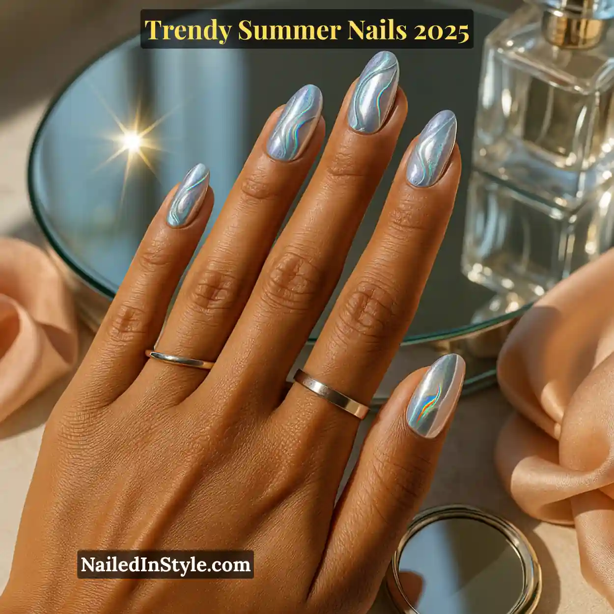 Trendy Summer Nails 2026: Top Designs, Colors & Ideas for the Season 17 Olive-toned hand with medium-length almond nails featuring holographic chrome swirls, touching a mirrored compact on a glass vanity tray.