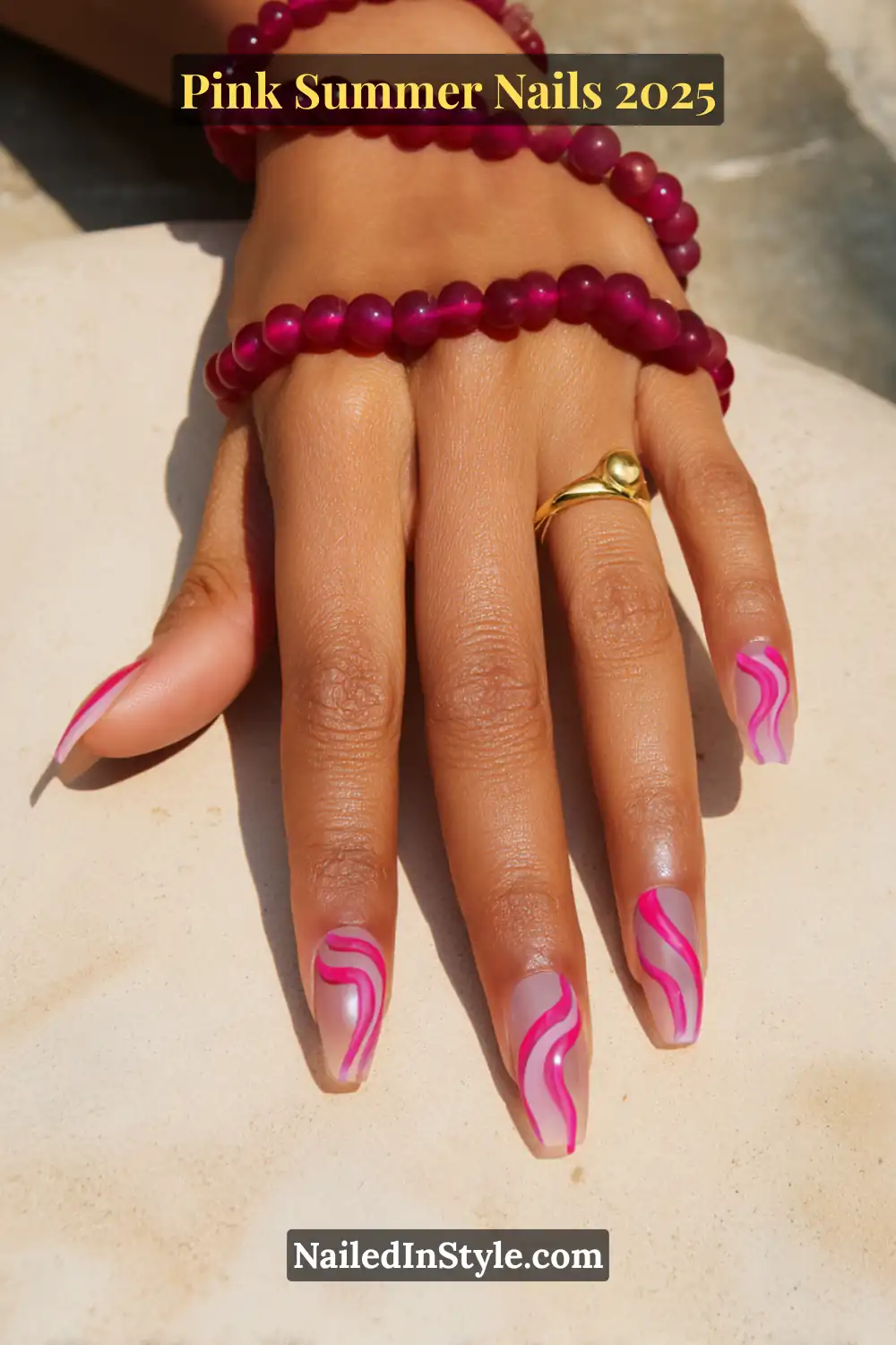 Hand with long square nails featuring nude matte base and vibrant hot pink abstract wave lines, paired with fuchsia beaded bracelets.
