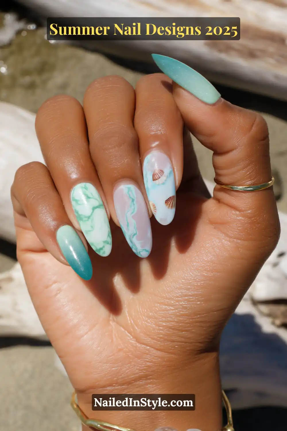 Beach-themed nail art featuring seafoam marble, ocean ombré, and tiny seashell decals on almond-shaped nails