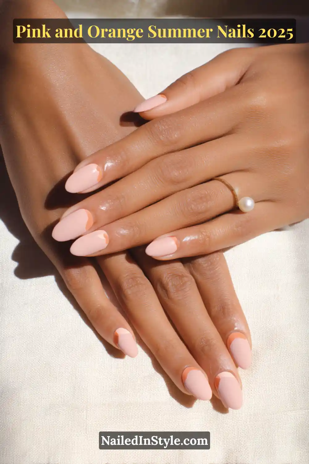 Pink and Orange Summer Nails 2026: Sunset Tips, Endless Vibes 19 Hands with almond-shaped nails in muted blush pink, each featuring a small tangerine moon detail near the cuticle, posed on medium skin with pearl and gold rings.