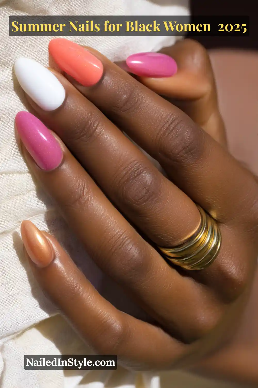 Close-up of a Black woman’s hand with oval nails in coral, fuchsia, white, pastel pink, and bronze chrome, styled with a stacked gold ring and soft natural lighting.