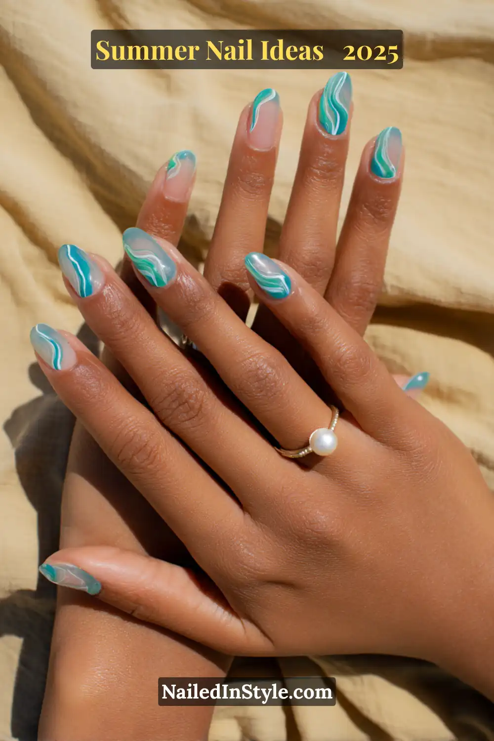 Two bronzed hands with almond-shaped nails featuring turquoise and mint green wave swirl French tips over a translucent nude base, photographed in sunlight on a sandy beige fabric background.