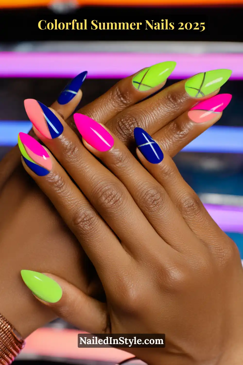 Colorful Summer Nails 2026: Bold, Fun & Bright Manicure Ideas 2 Two hands with deep brown skin tone featuring almond-shaped nails in neon pink, lime green, cobalt blue, and peach, with geometric and crisscross line designs
