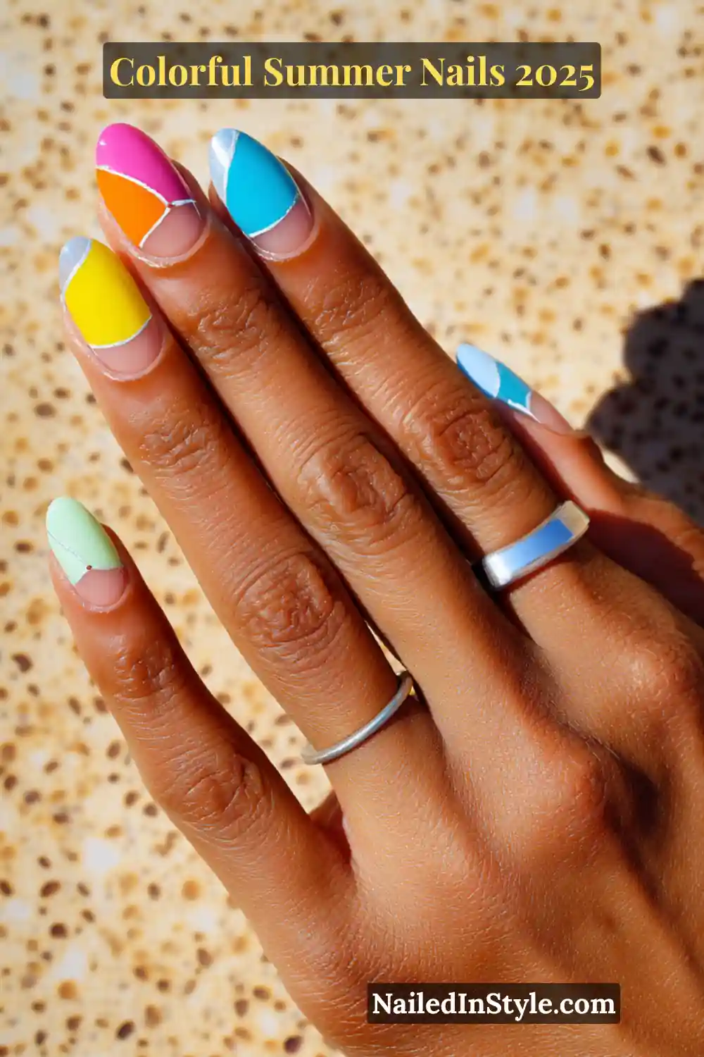 Colorful Summer Nails 2026: Bold, Fun & Bright Manicure Ideas 21 Hand with medium brown skin tone featuring almond-shaped nails with bold geometric color blocks in pink, orange, yellow, mint green, and blue outlined with fine silver lines