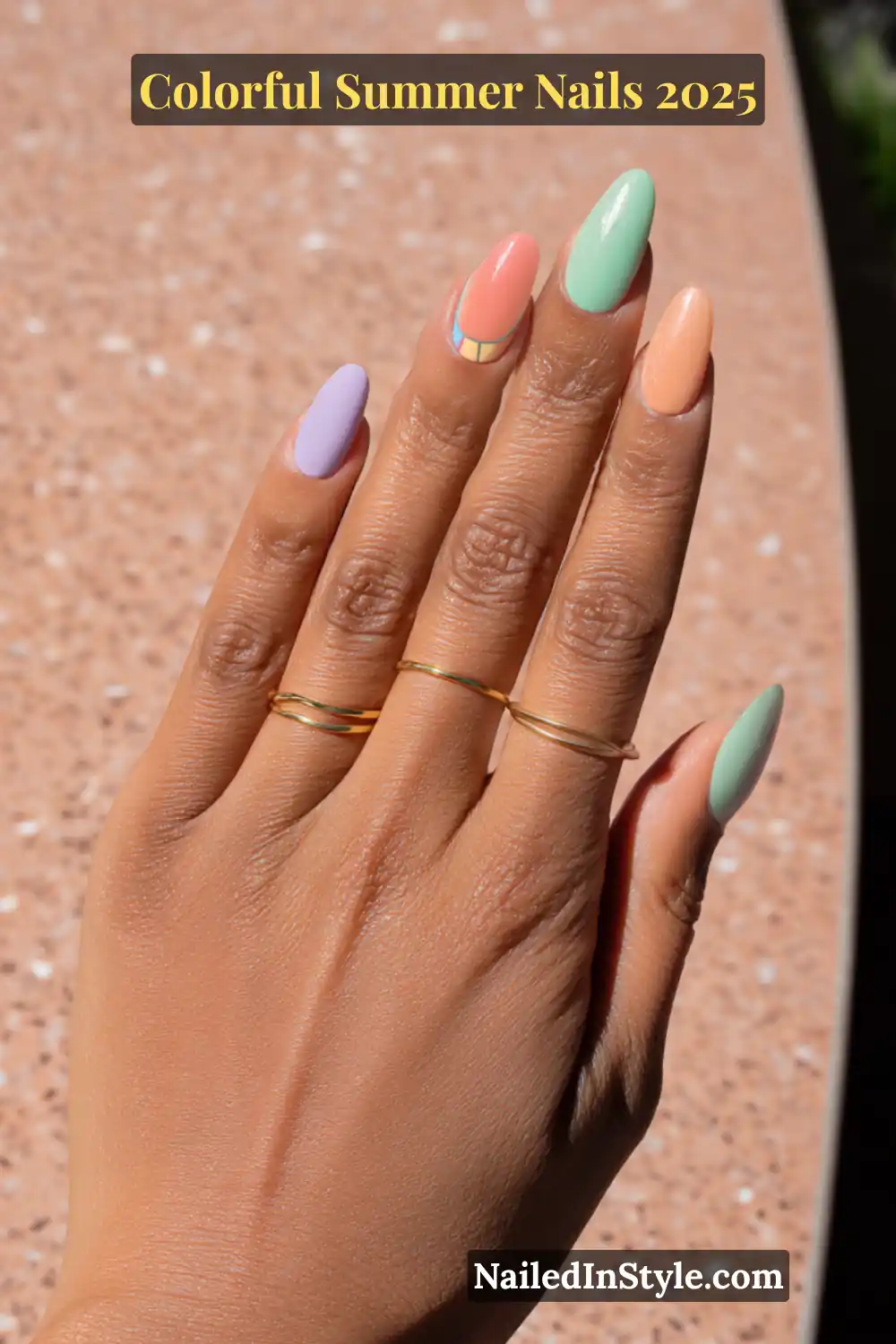 Colorful Summer Nails 2026: Bold, Fun & Bright Manicure Ideas 9 Hand with light golden skin tone featuring almond-shaped nails in mint green, peach, lavender, and a color-blocked accent design