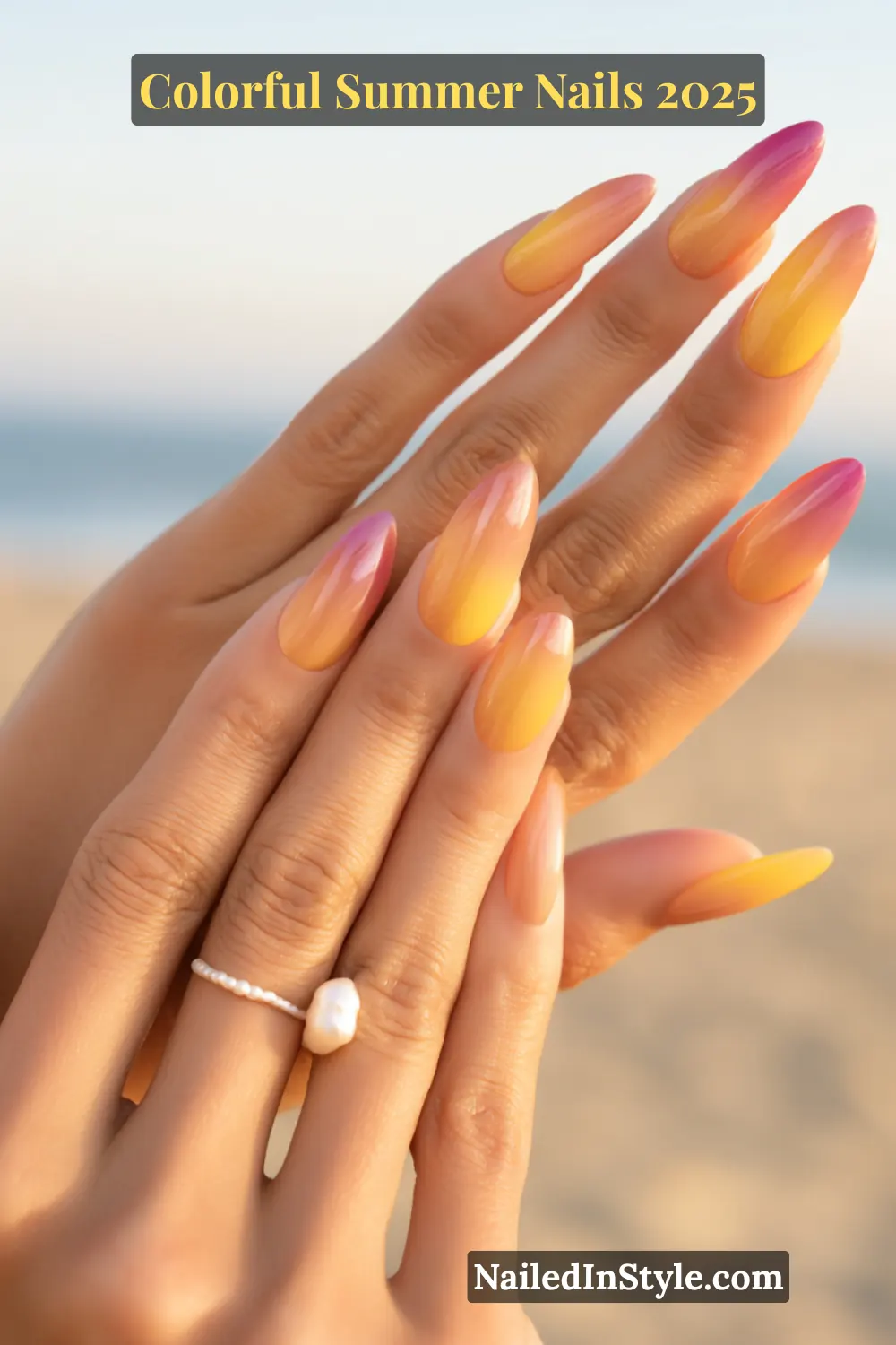 Colorful Summer Nails 2026: Bold, Fun & Bright Manicure Ideas 18 Two hands with light skin tone featuring almond-shaped nails with ombré tips fading from magenta to orange to yellow, set against a beach background