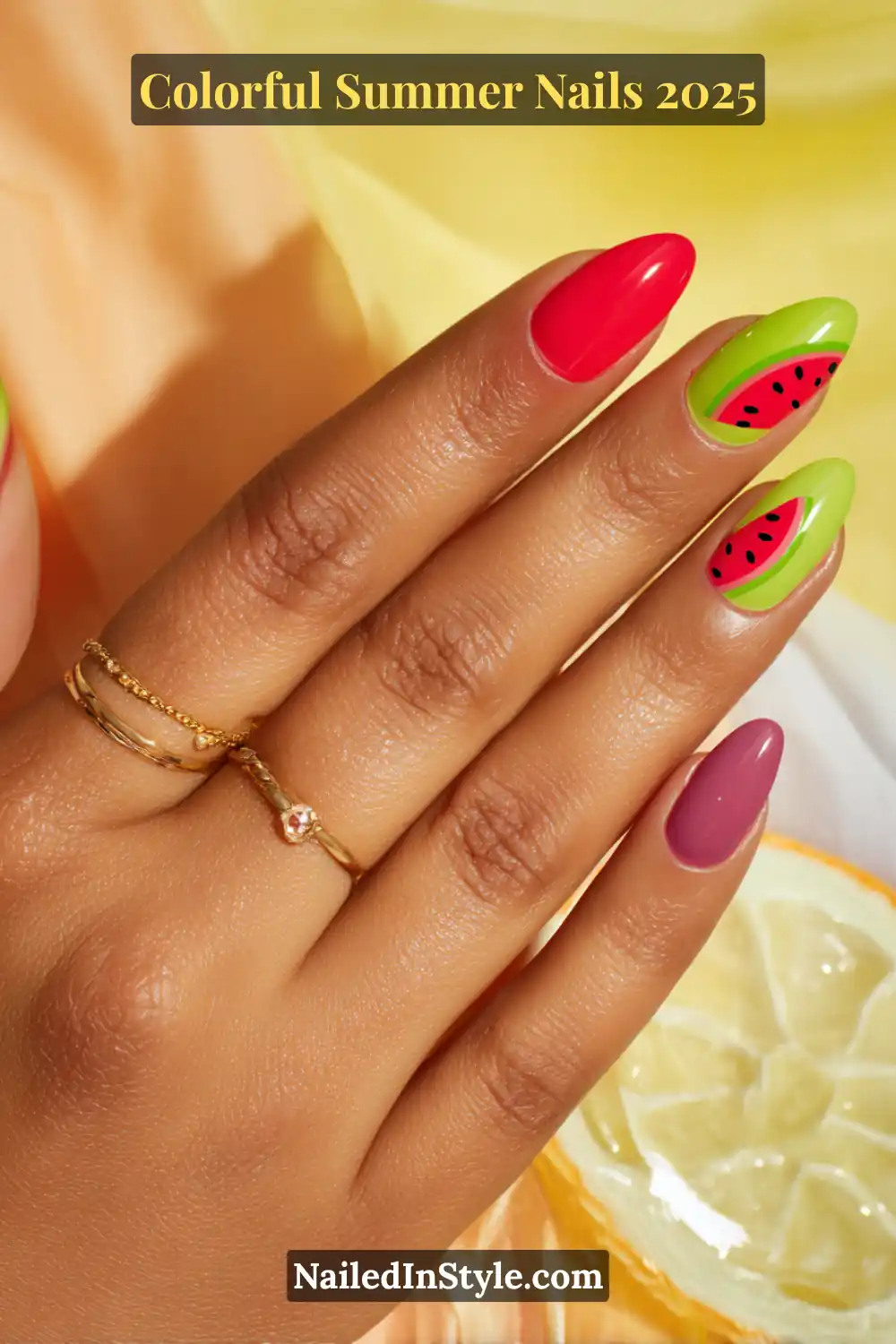 Colorful Summer Nails 2026: Bold, Fun & Bright Manicure Ideas 5 Hand with medium tan skin tone featuring almond-shaped nails in watermelon red, kiwi green with black seed designs, and berry pink
