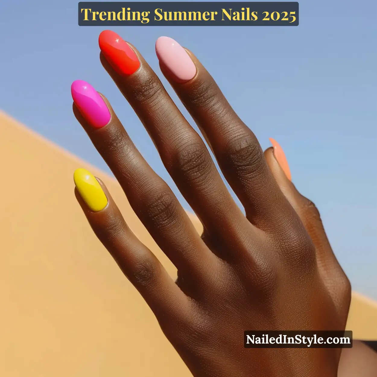 Deep-toned hand with glossy oval nails in bold yellow, hot pink, coral red, baby pink, and peach against a clear sky and desert sand background.