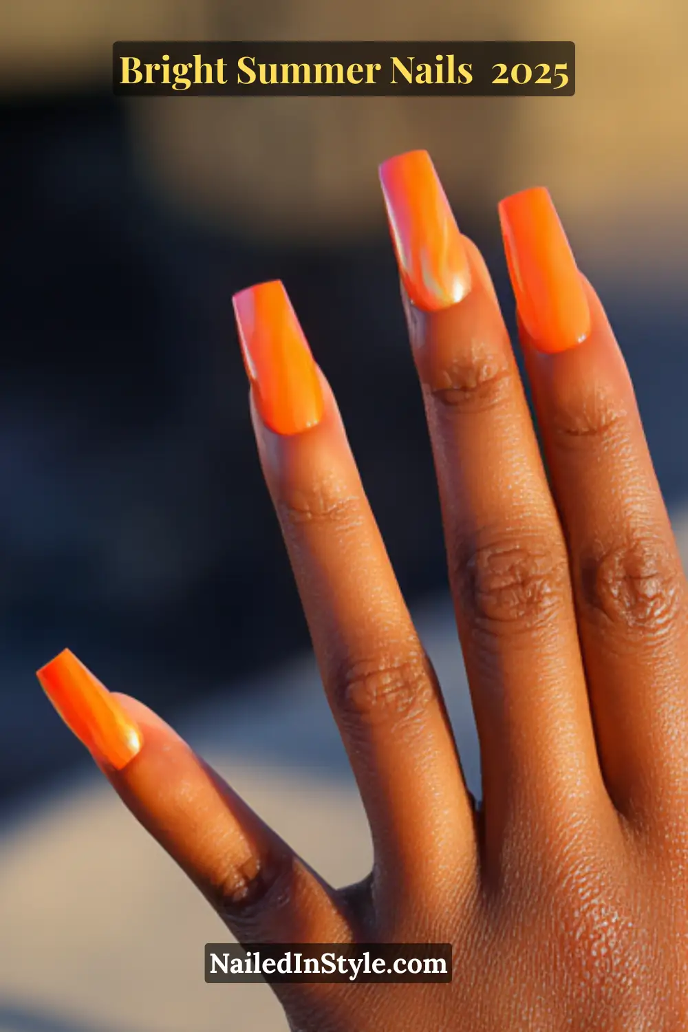 Close-up of a hand with glossy electric orange coffin nails, glowing with a fiery sunset-inspired summer look.