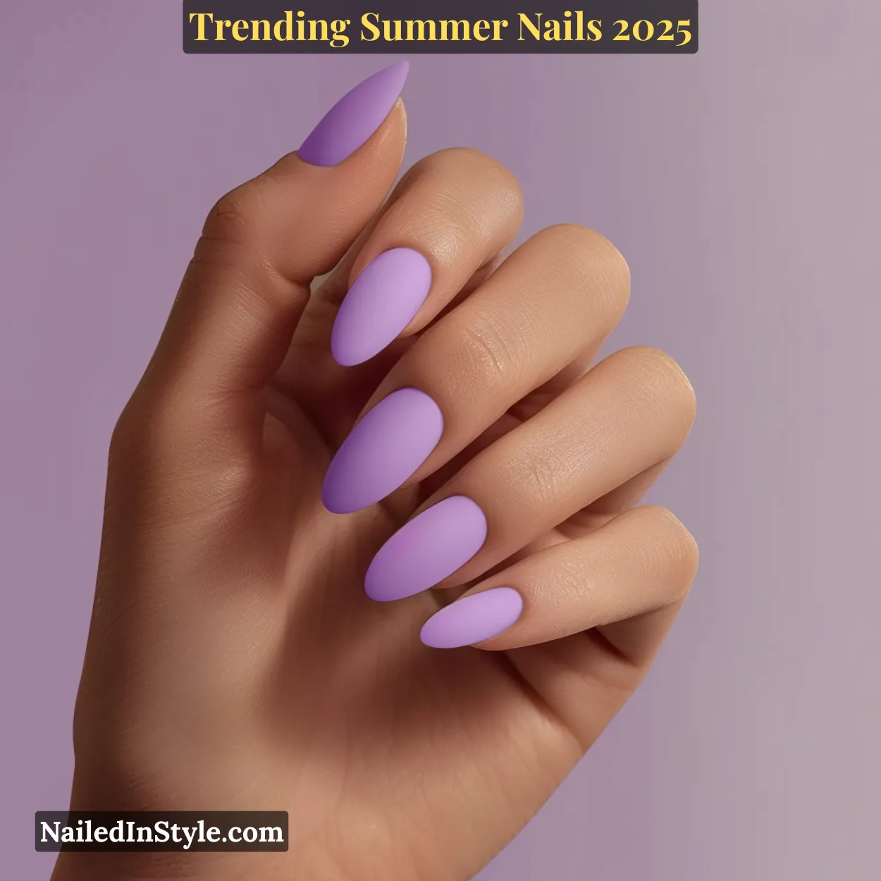A medium-toned hand with almond-shaped matte lavender nails, posed against a lavender-toned background.