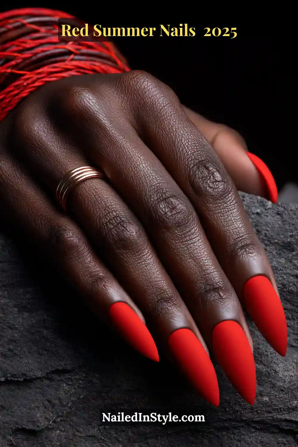 Red Summer Nails 2026: Bold, Fiery & Classic Warm-Weather Looks 12 Close-up of matte tomato red stiletto nails on deep skin with stacked copper rings and red thread bracelets