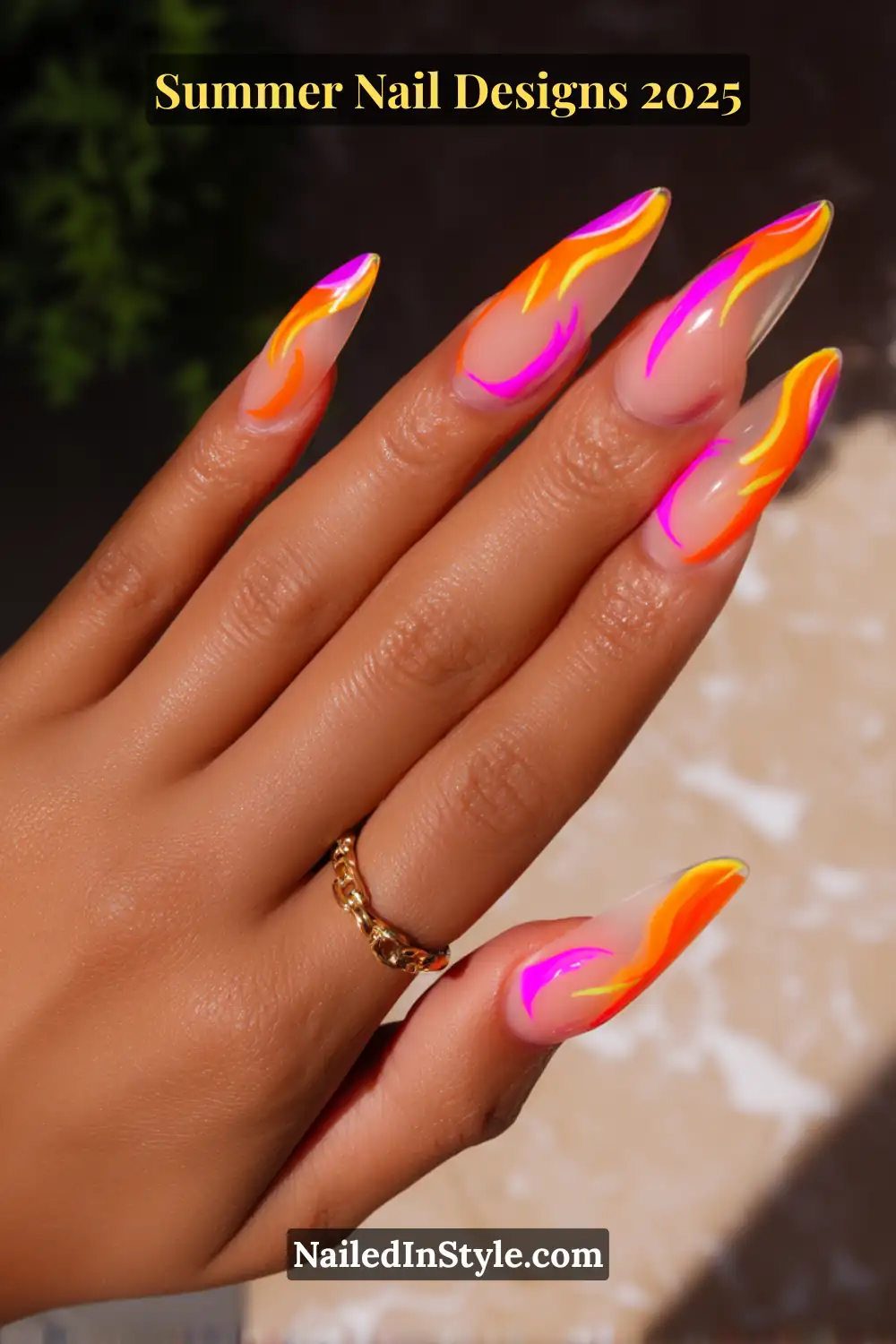 Long almond nails with neon flame art in orange, pink, and yellow on a natural-toned base