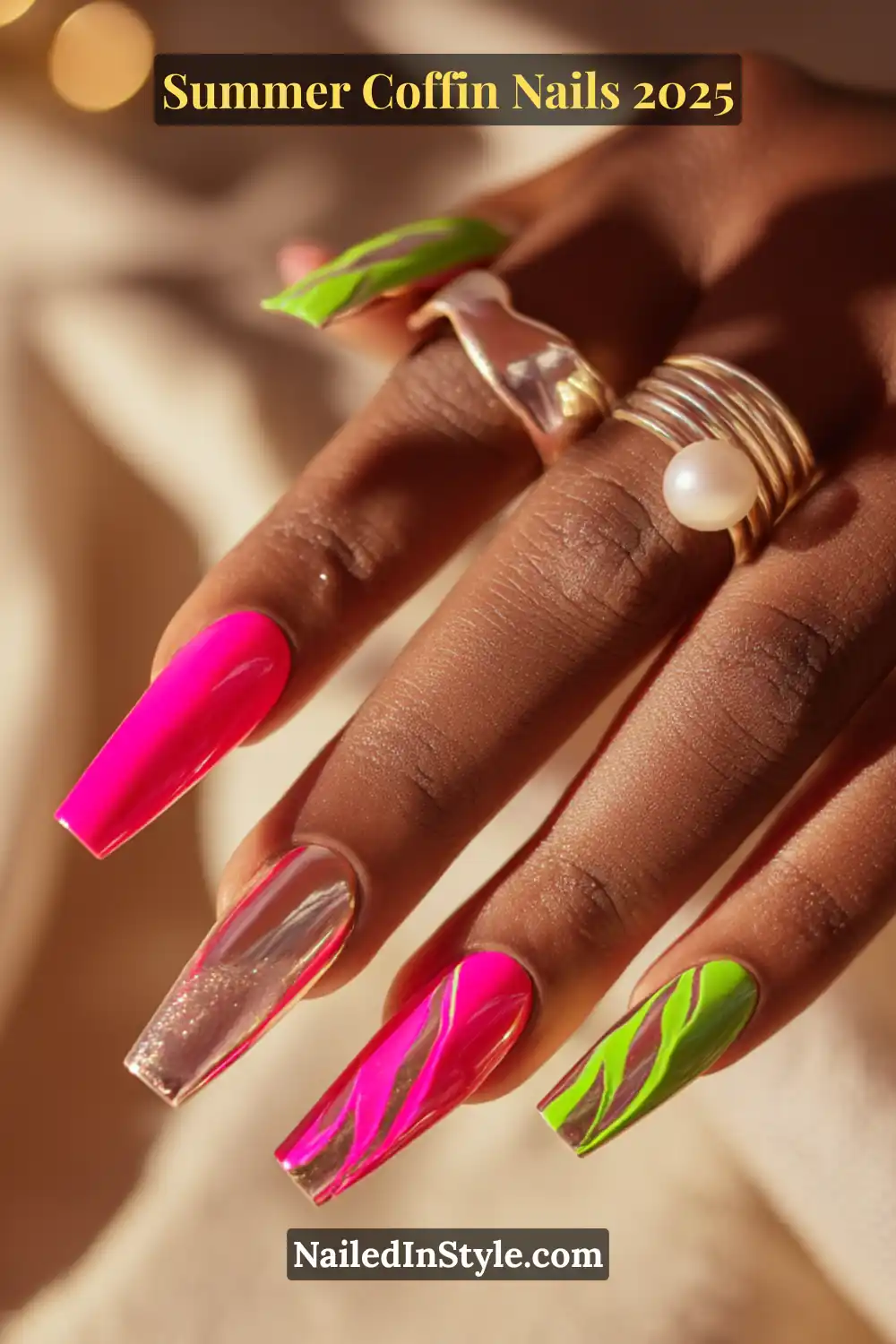 Deep-toned hand with coffin nails in fuchsia, electric green, and metallic chrome, accented by abstract swirls and gold pearl rings.