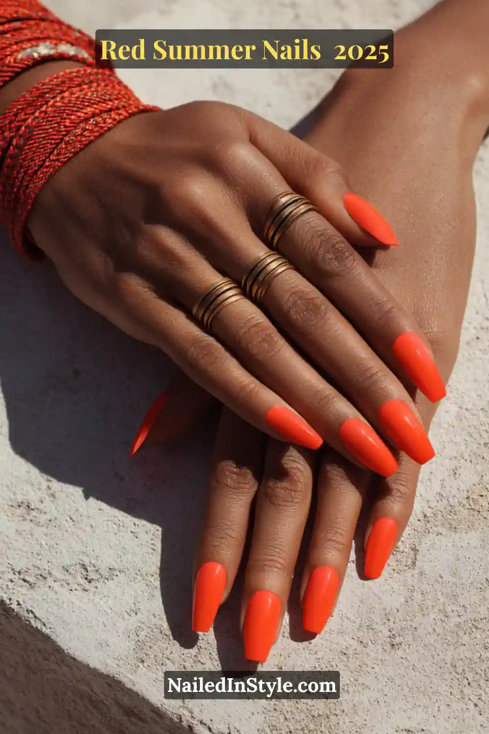 Red Summer Nails 2026: Bold, Fiery & Classic Warm-Weather Looks 11 Vibrant neon red coffin-shaped nails on deep skin with stacked gold rings and red woven bracelets