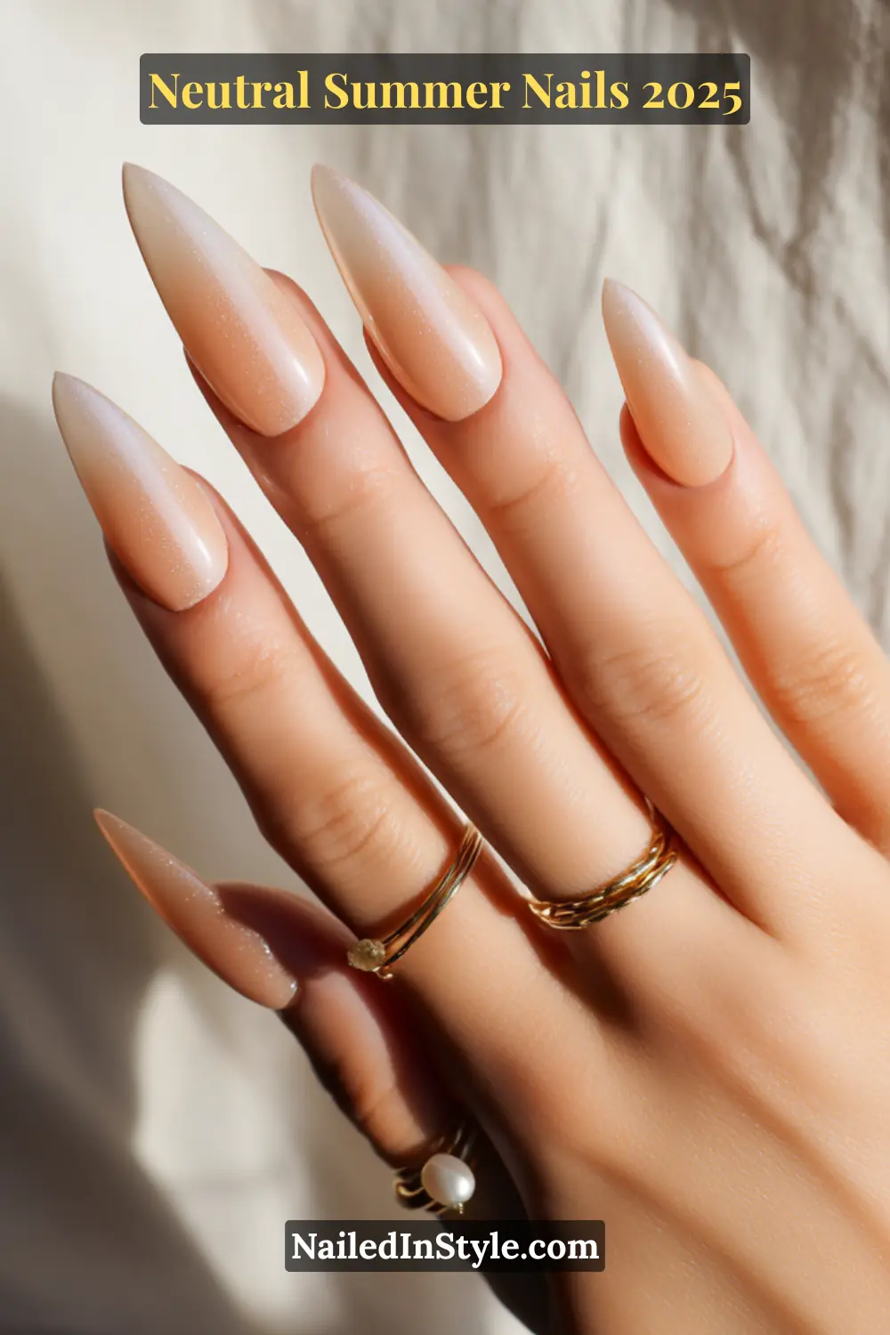 Neutral Summer Nails 2026: Clean, Chic & Warm-Weather Ready 17 Hand with almond-shaped nails featuring a beige chrome ombré effect, shimmering under natural light and styled with layered gold rings.
