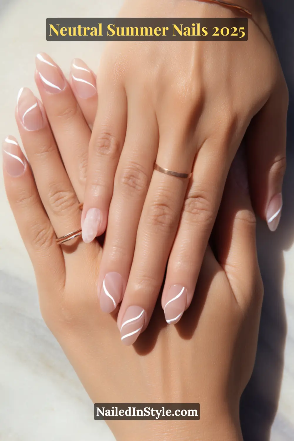 Neutral Summer Nails 2026: Clean, Chic & Warm-Weather Ready 16 Two hands with almond-shaped nails featuring minimalist white swirl nail art over a nude base, paired with rose gold rings.