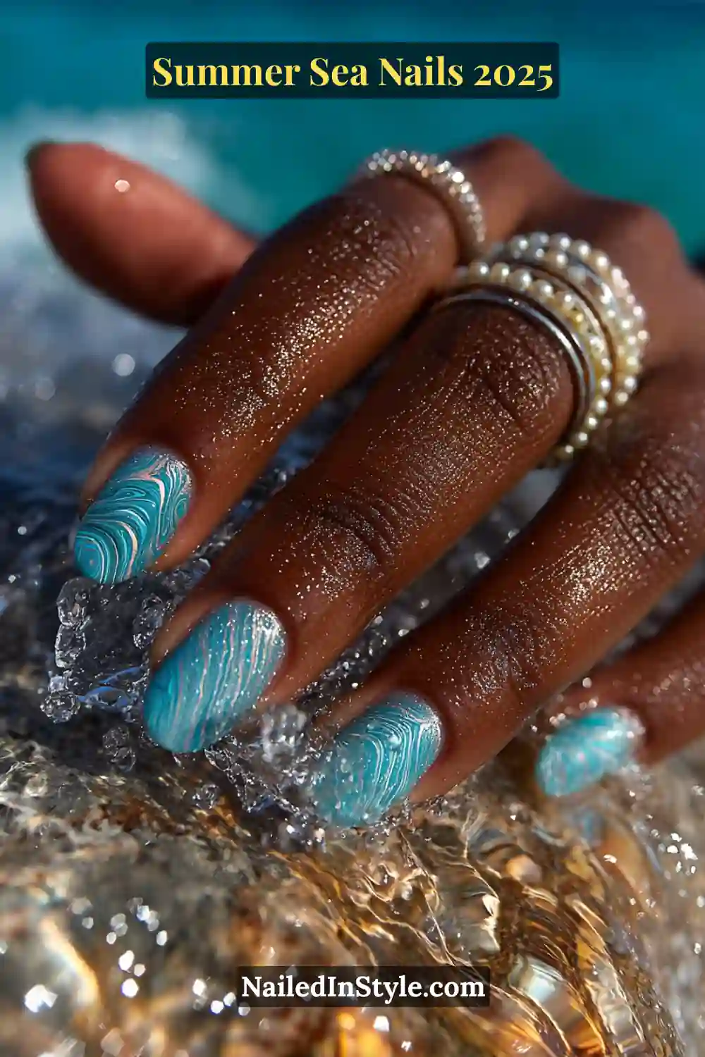 Hand with ocean swirl marble nail art in turquoise and white tones, splashing in clear beach water