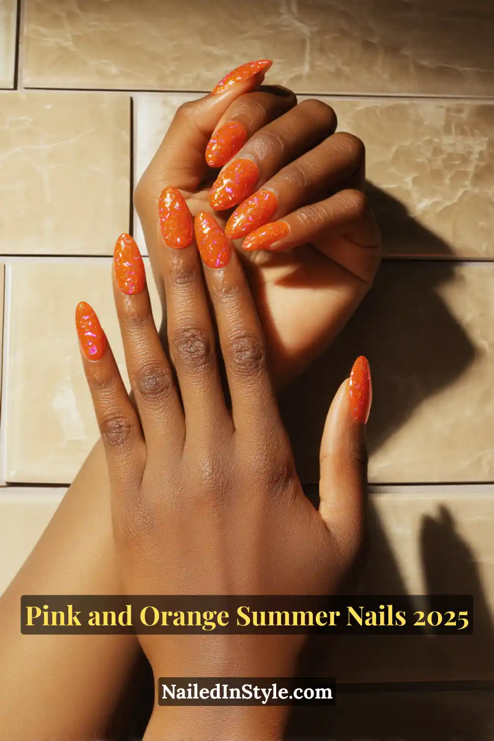 Pink and Orange Summer Nails 2026: Sunset Tips, Endless Vibes 9 Hands with almond-shaped nails in a glossy orange base with pink foil flakes, shown in a relaxed pose on medium-deep skin against tiled background.