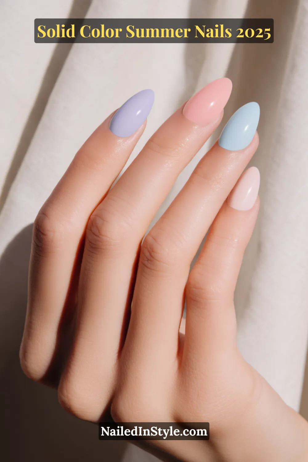 A hand with long almond-shaped nails painted in soft pastel tones including lavender, peach, aqua, and blush pink, shown against a light fabric background.