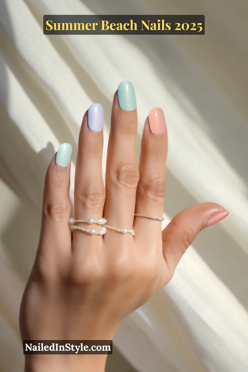 Summer Beach Nails 2026: Tropical, Trendy & Totally You 7 Close-up of fair-skinned hand with pastel beach nails in soft mint, peach, sky blue, and lilac with a glossy shimmer finish