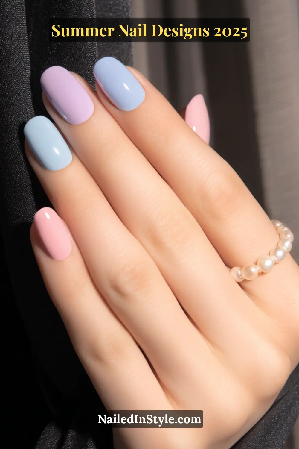 Fair-skinned hand with soft pastel nail polish in sky blue, lilac, and baby pink tones for a chic summer look