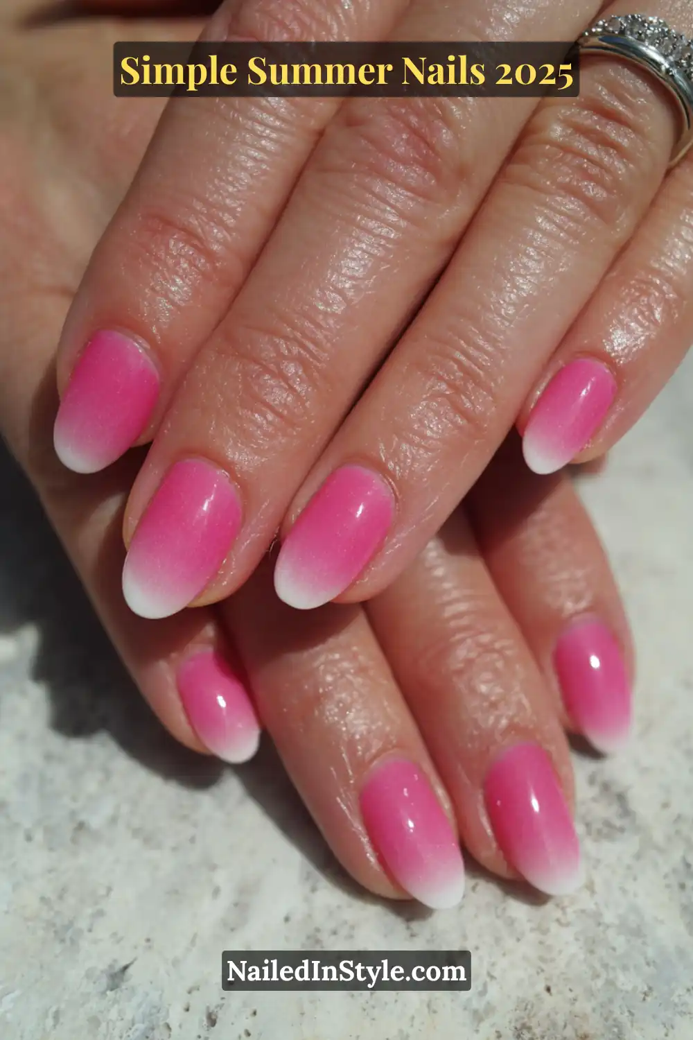 Natural hands with almond-shaped nails featuring a gradient ombré effect that fades from bold pink at the base to soft white at the tips.
