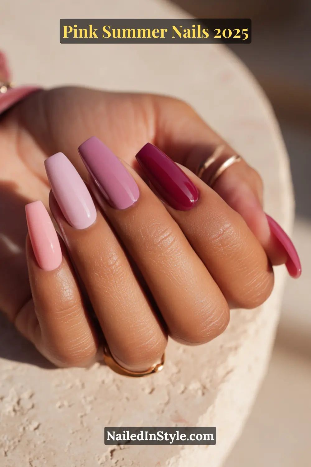 Close-up of olive skin hand with long square nails in shades of mauve, dusty rose, and raspberry pink