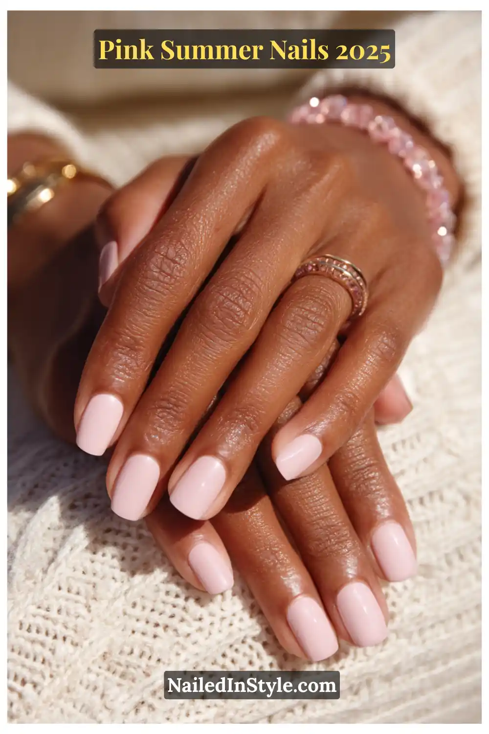 Close-up of hands with short squoval nails painted in glossy ballet pink gel polish, accessorized with a blush gemstone ring and bracelet