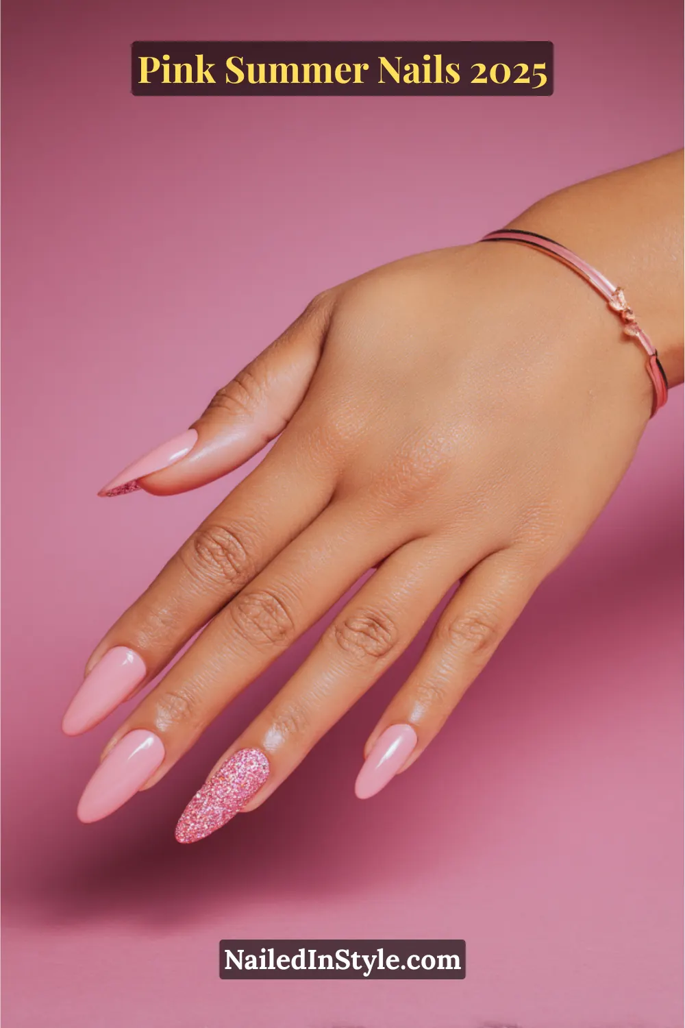 Hand with glossy pink almond nails featuring a full-glitter accent on the ring finger, posed on a pink background.