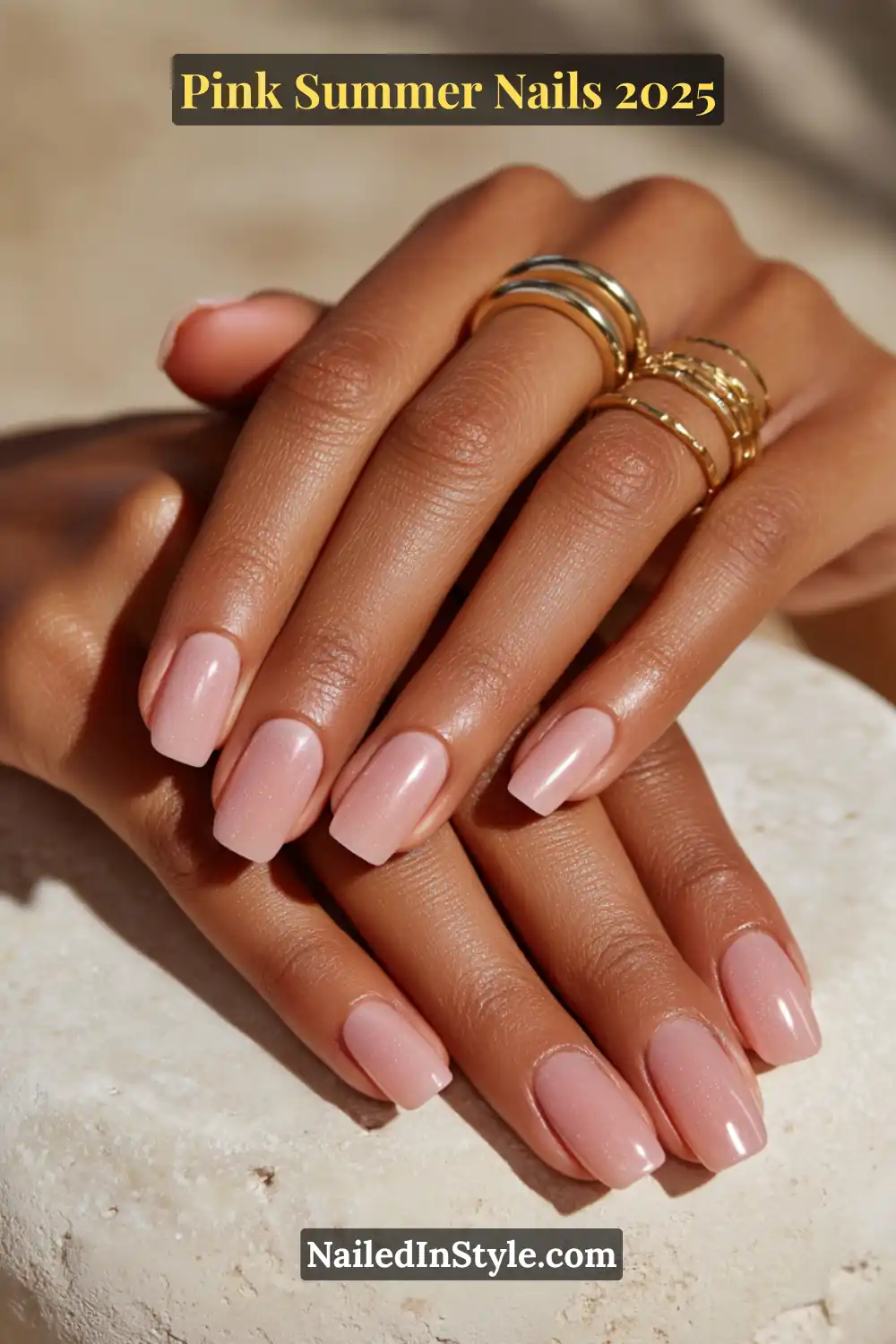 Close-up of hands with glossy blush BIAB overlay on square nails, worn with gold rings on medium skin tone