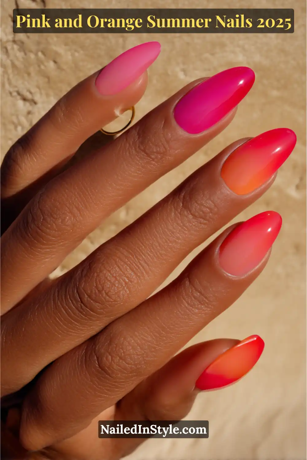 Pink and Orange Summer Nails 2026: Sunset Tips, Endless Vibes 6 Hand with almond-shaped nails featuring vertical pink-to-orange ombré gradients, shown in a gentle arch against a sunlit textured surface.