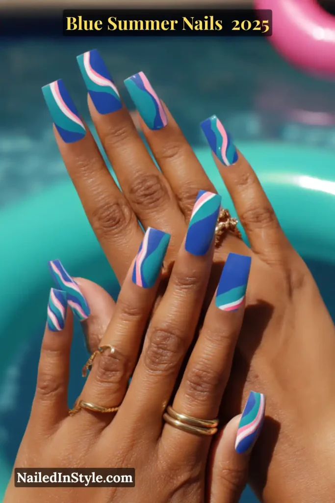 Hands with neon blue nails featuring bold color-block and swirl designs in teal, pink, and white, styled for a summer poolside vibe.