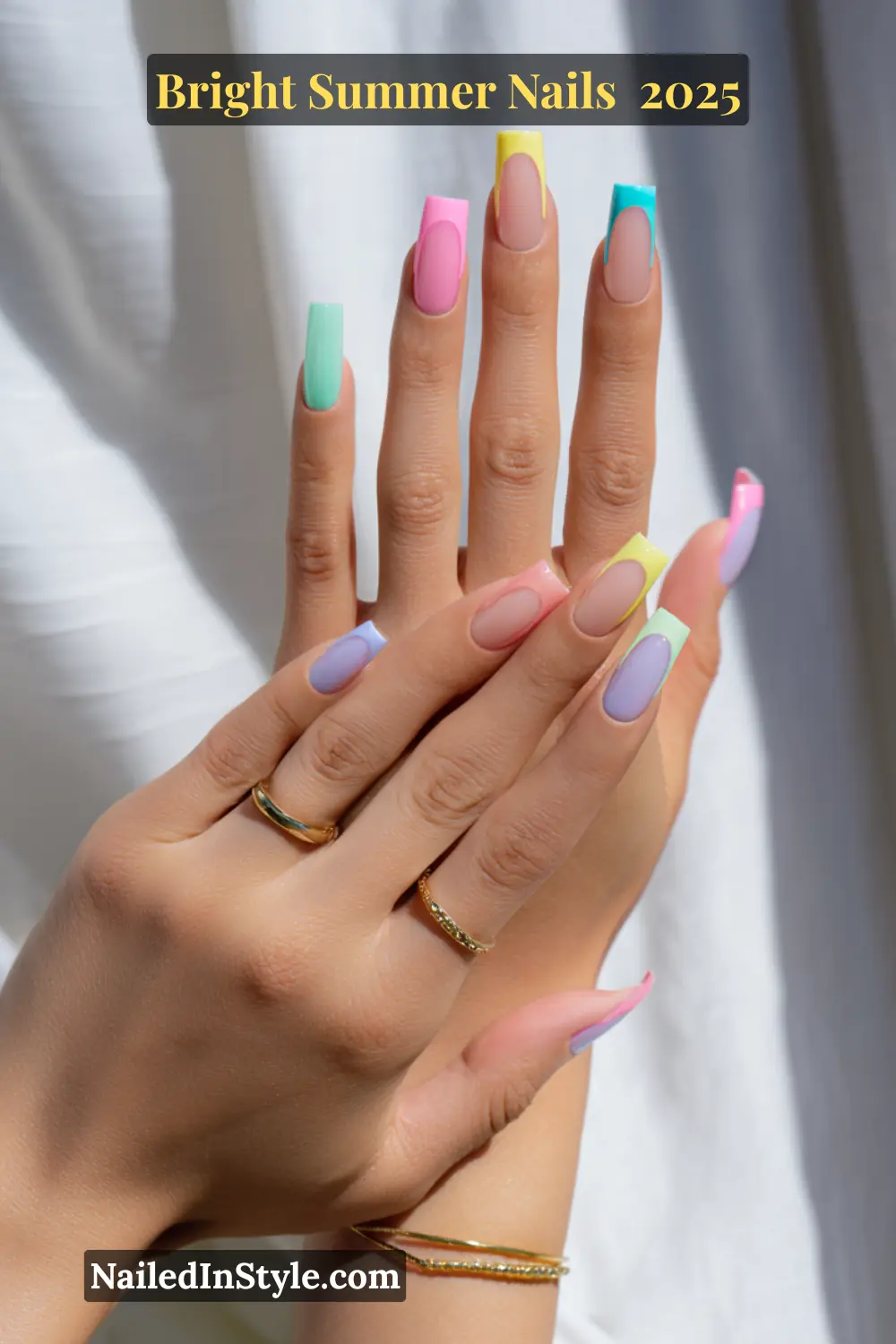 Two hands with fair skin show pastel rainbow French tip nails, each tip in a different color like pink, mint, lilac, and yellow, against a bright background.