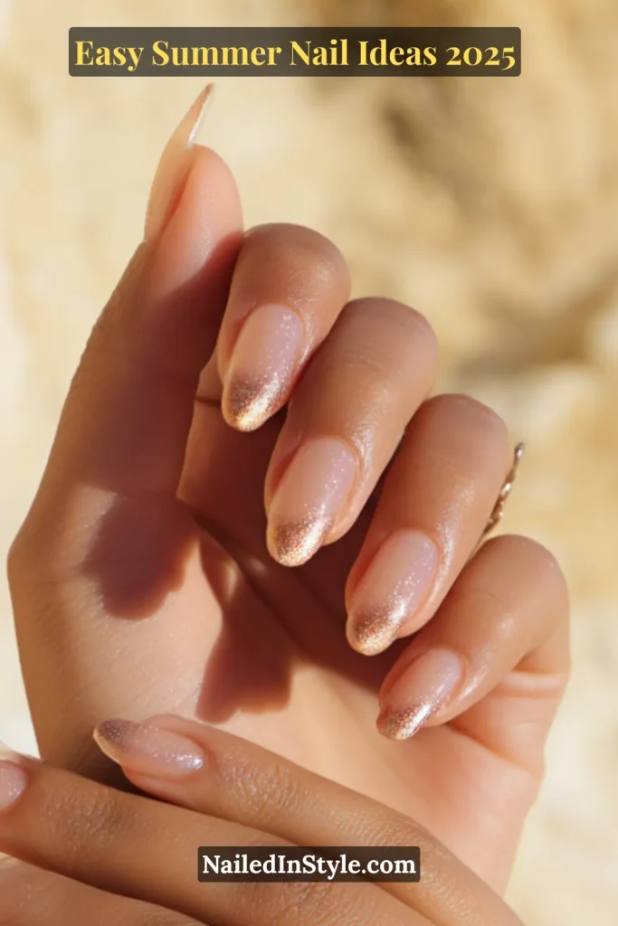 Hand with almond-shaped nails painted in a soft nude base with shimmering rose gold metallic tips; elegant and glowing under natural summer sunlight.