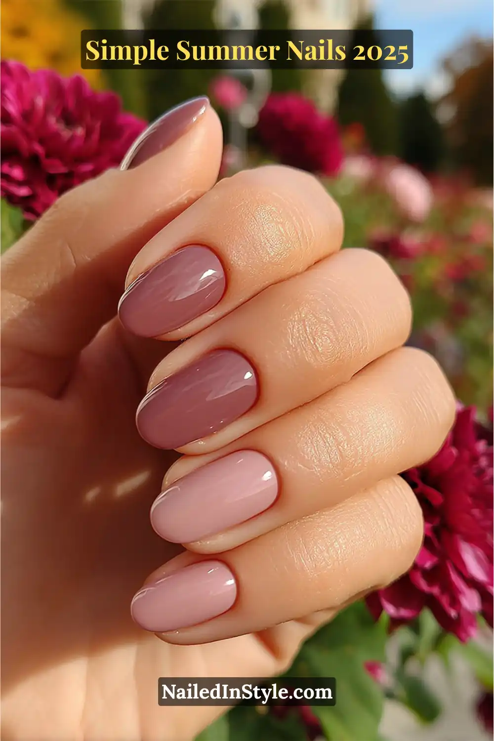 Almond-shaped nails painted in soft rose and mauve shades, styled on a well-groomed hand with a blooming floral background.