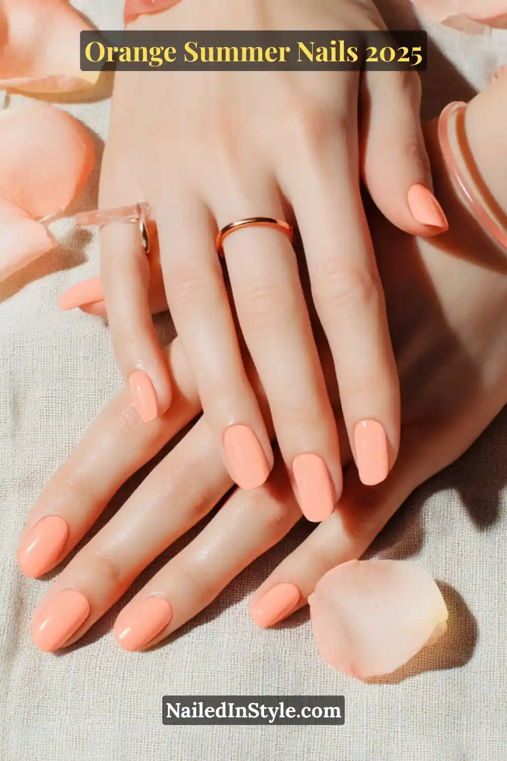Close-up of hands with light coral squoval nails, styled with dainty rose gold rings and soft pink rose petals on a linen surface.