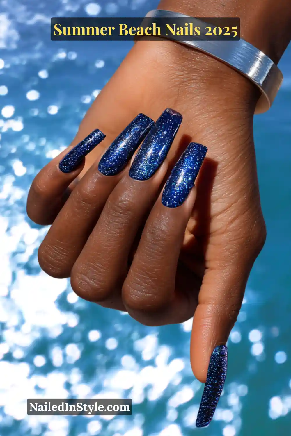 Summer Beach Nails 2026: Tropical, Trendy & Totally You 6 Long coffin-shaped nails painted in deep cobalt blue glitter polish, shimmering in sunlight near the ocean