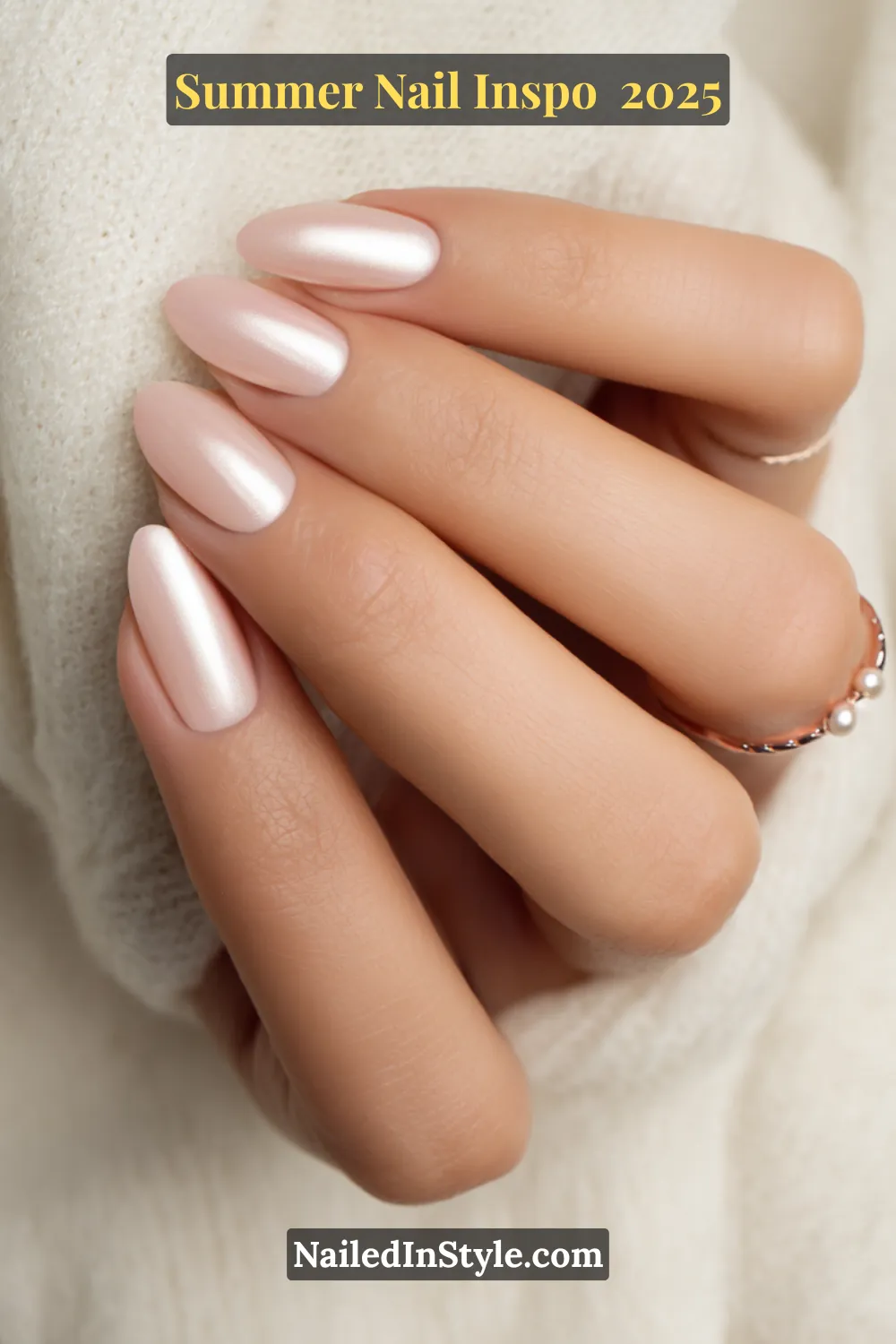 Close-up of a hand with almond-shaped nails in a soft pearlescent chrome finish resembling seashell shimmer, paired with a delicate pearl ring.