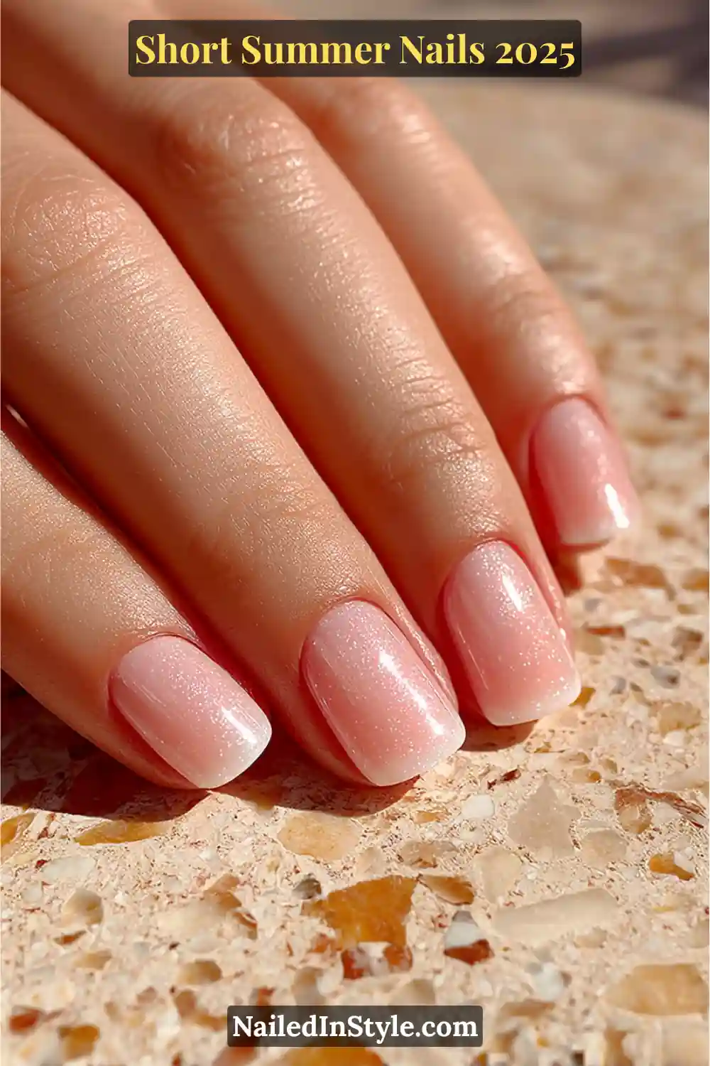 Close-up of a hand with short rounded nails coated in a sheer latte-toned BIAB overlay with a glossy shimmer finish.