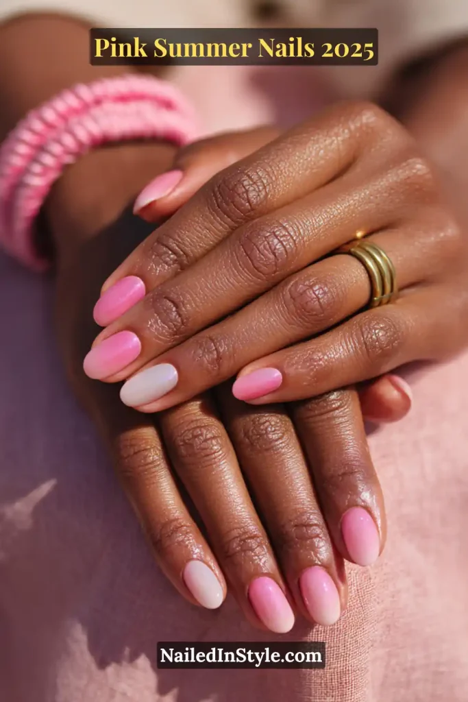 Close-up of hands with short rounded nails painted in soft pink and nude shades for summer 2025