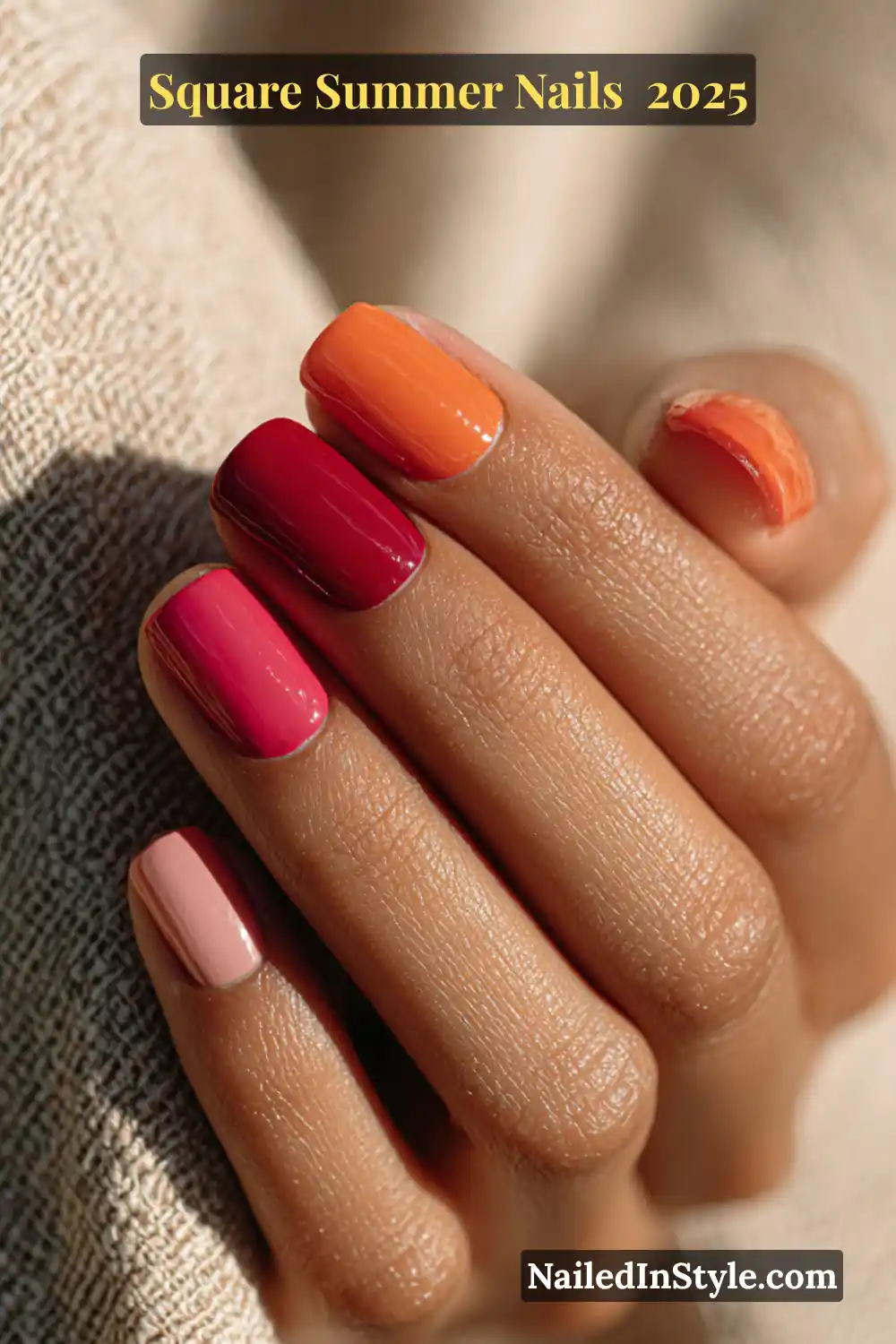 Medium-toned hand with square-shaped nails in a sunset-inspired gradient — soft pink, coral, red, tangerine, and orange polish finishes