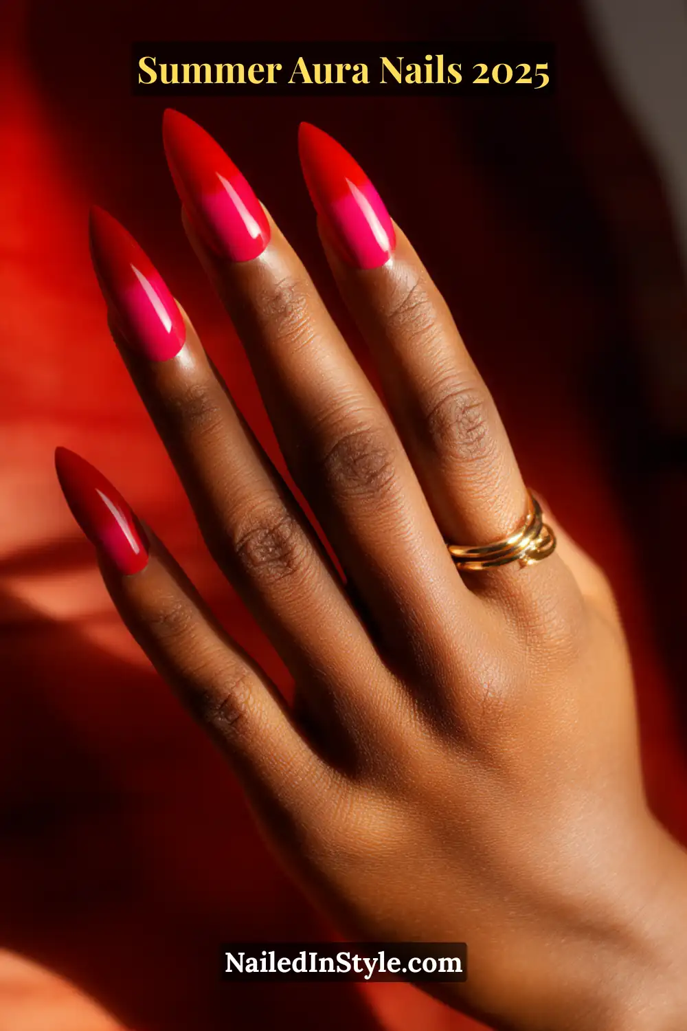Close-up of deep skin hand with stiletto nails in electric red center and hot pink aura glow—bold summer 2025 manicure