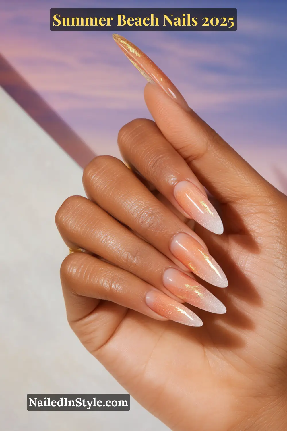 Summer Beach Nails 2026: Tropical, Trendy & Totally You 15 Close-up of one hand with almond-shaped ombre sunset nails in peach and white, accented with gold foil, against a soft sky background