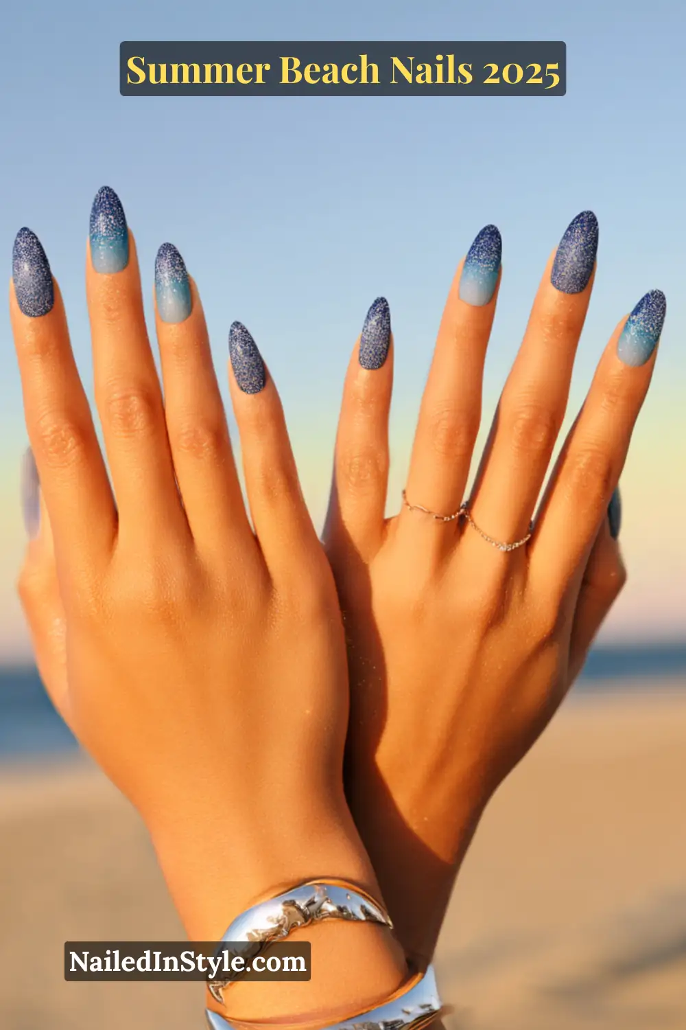 Summer Beach Nails 2026: Tropical, Trendy & Totally You 21 Two hands with ombré nails blending from sky blue to navy, accented with silver shimmer, against beach background