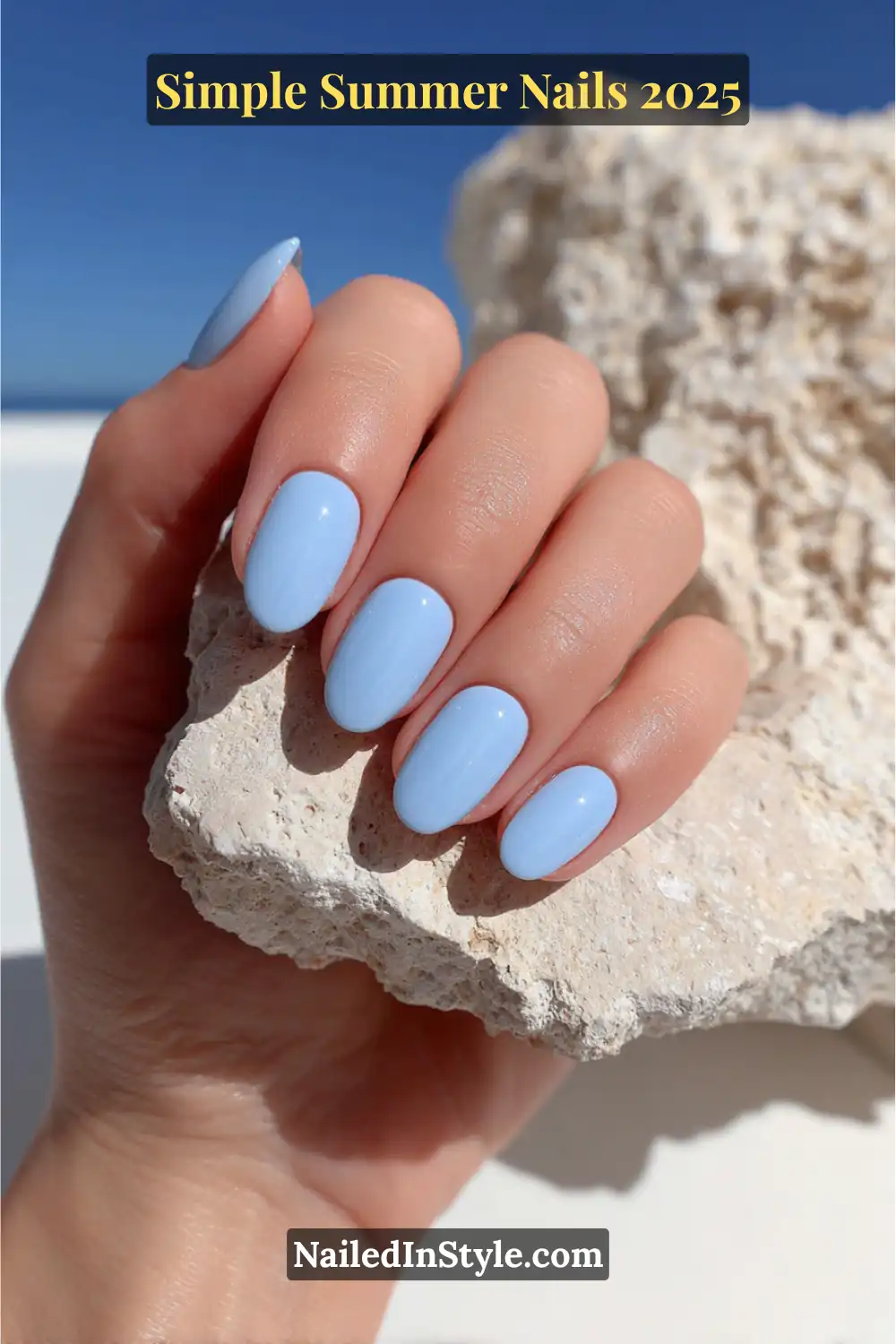 Almond-shaped nails painted in glossy sky blue, photographed in natural sunlight against a light stone and blue sky background.