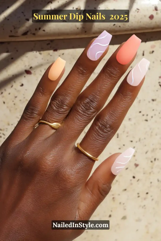 A hand with square-shaped summer dip nails in soft pastel tones, featuring matte peach, coral, lavender, and glossy swirl accents under sunlight.