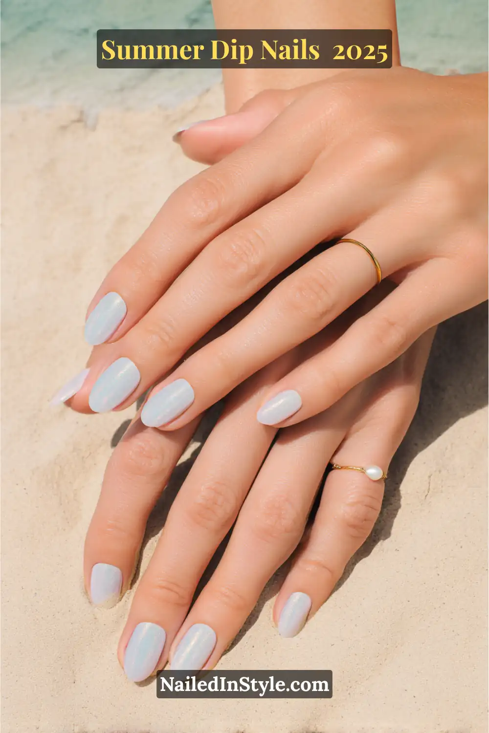 Close-up of hands with short, rounded nails painted in a translucent mint shimmer chrome, resting on sandy beach background.