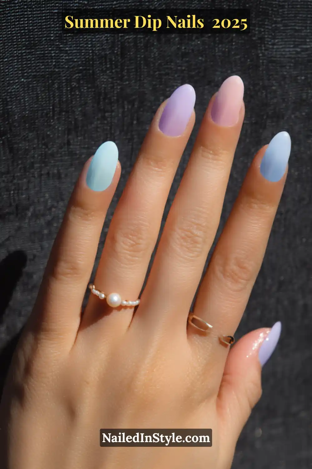 Hand with almond-shaped nails painted in soft pastel dip powders including baby pink, lilac, and sky blue—perfectly suited for fair skin tones.