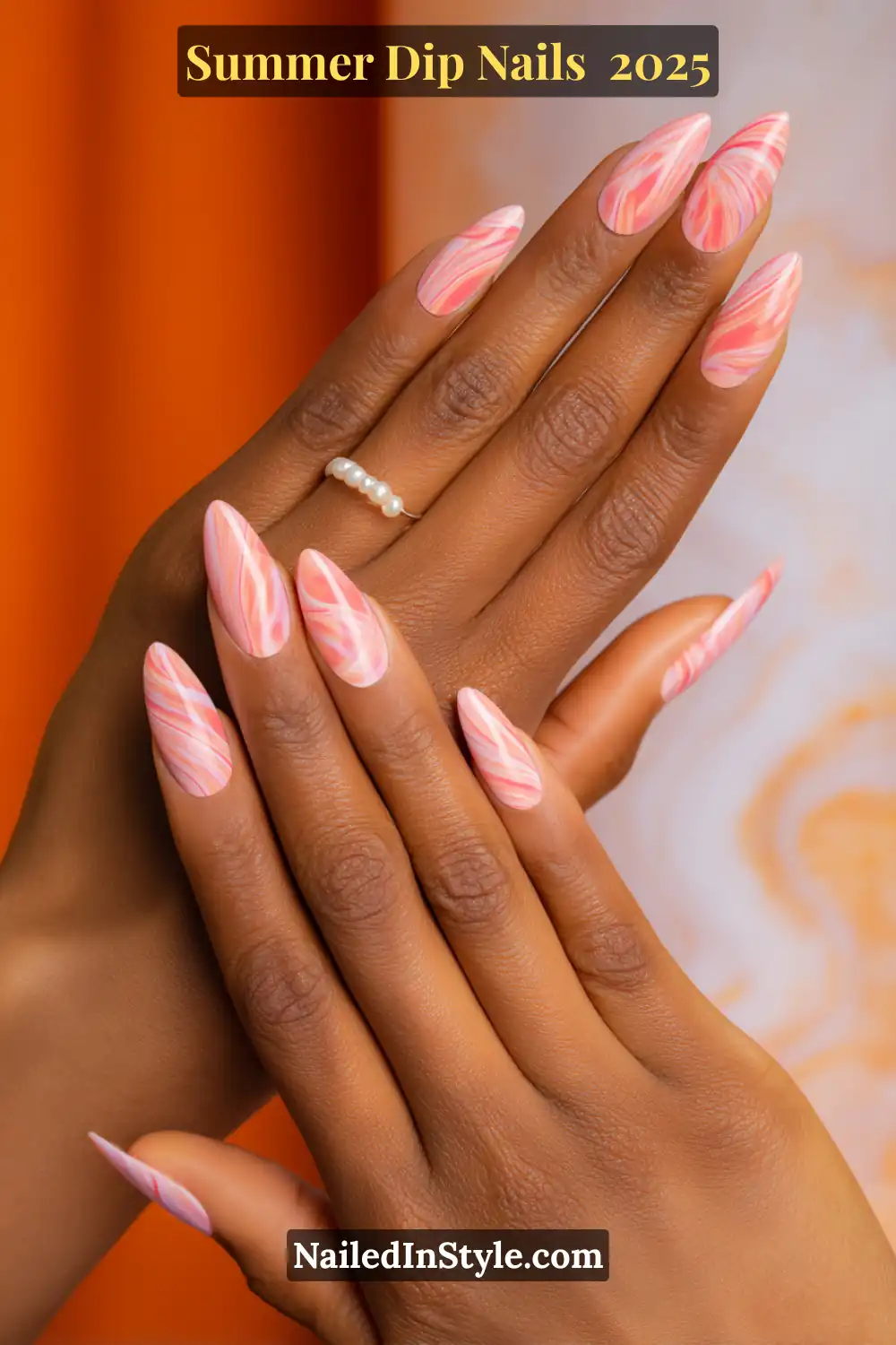 Close-up of hands featuring almond-shaped nails with coral and pink swirl dip design, resembling a vivid tropical sky.