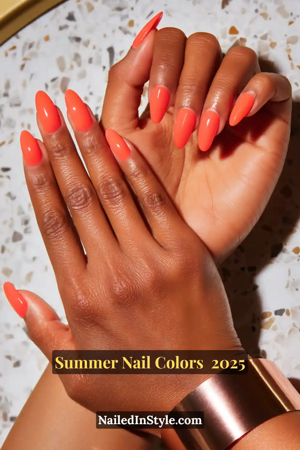Hottest Summer Nail Colors 2026: Bold, Breezy & On-Trend 14 Close-up of dark-toned hands with almond-shaped nails in a striking neon-orange coral, glowing under direct light.